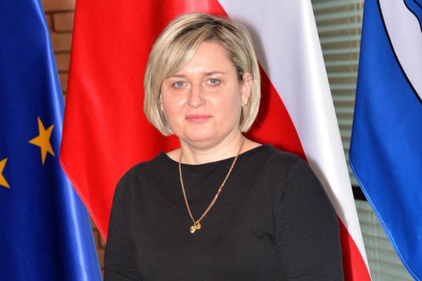 Zdjęcie portretowe kobiety – krótkie jasne włosy, ubrana jest w czarną bluzkę.