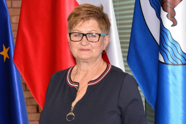 Zdjęcie portretowe kobiety – krótkie jasne włosy, okulary, ubrana jest w granatową bluzkę.