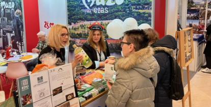 Stoisko promocyjne, hostessa podaje butelkę innej kobiecie.
