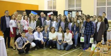 Duża grupa młodzieży szkolnej i nauczycieli w dużej sali szkolnej